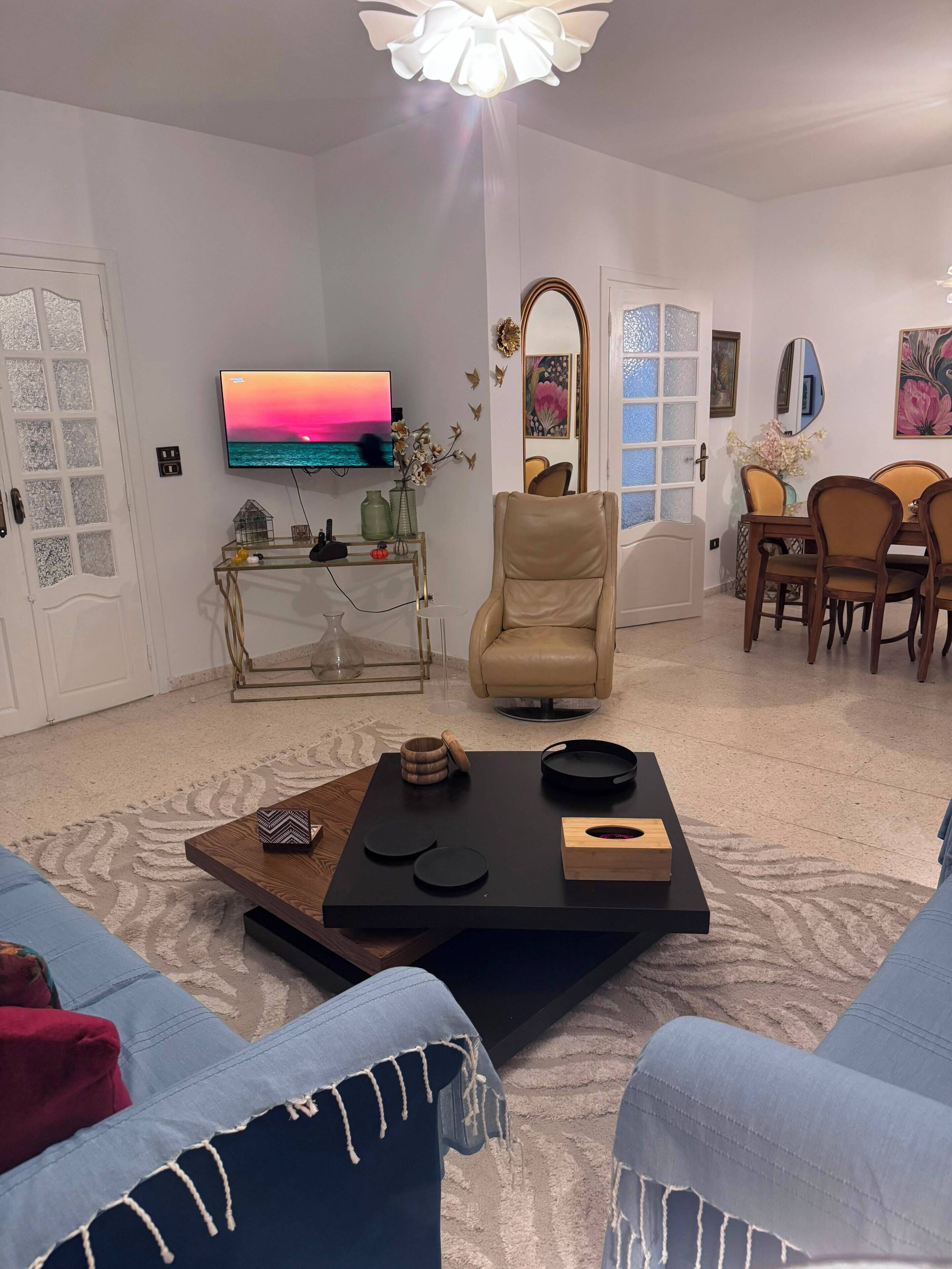 Un salon comprenant un téléviseur, un canapé, une table basse et un coin repas avec des chaises et une table.