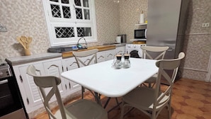 A compact kitchen with a dining table, chairs, a refrigerator, a microwave, and a washing machine. - The House of Olive Trees (La Marsa)