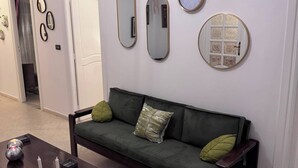 A living room with a green sofa, a wooden coffee table, and wall-mounted clocks. - The House of Olive Trees (La Marsa)
