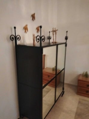 Um móvel com estrutura de metal espelhado e superfície refletora, posicionado contra uma parede lisa.
