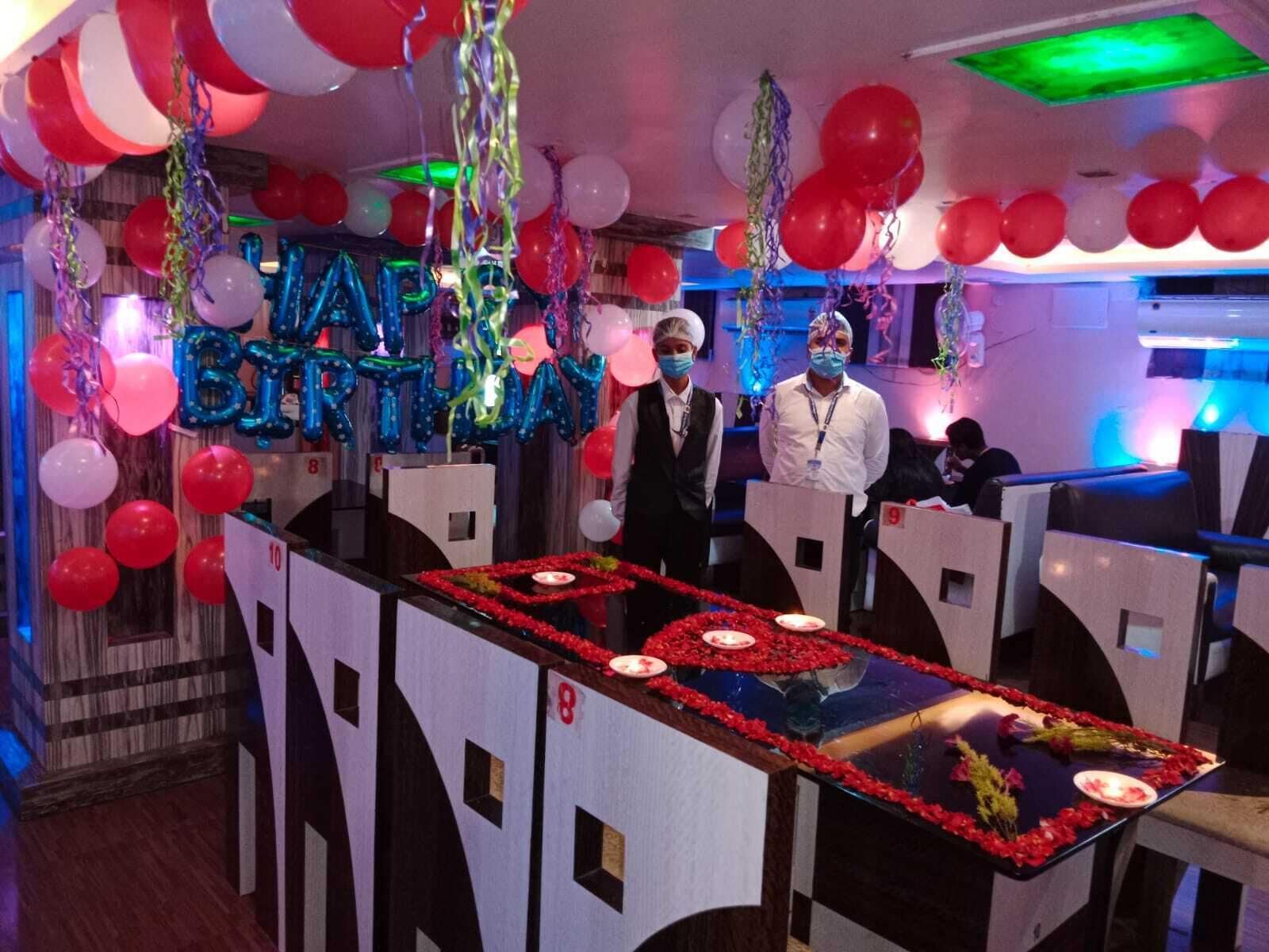 A bar area with a counter, red flower decorations, and balloons.