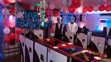A bar area with a counter, red flower decorations, and balloons.