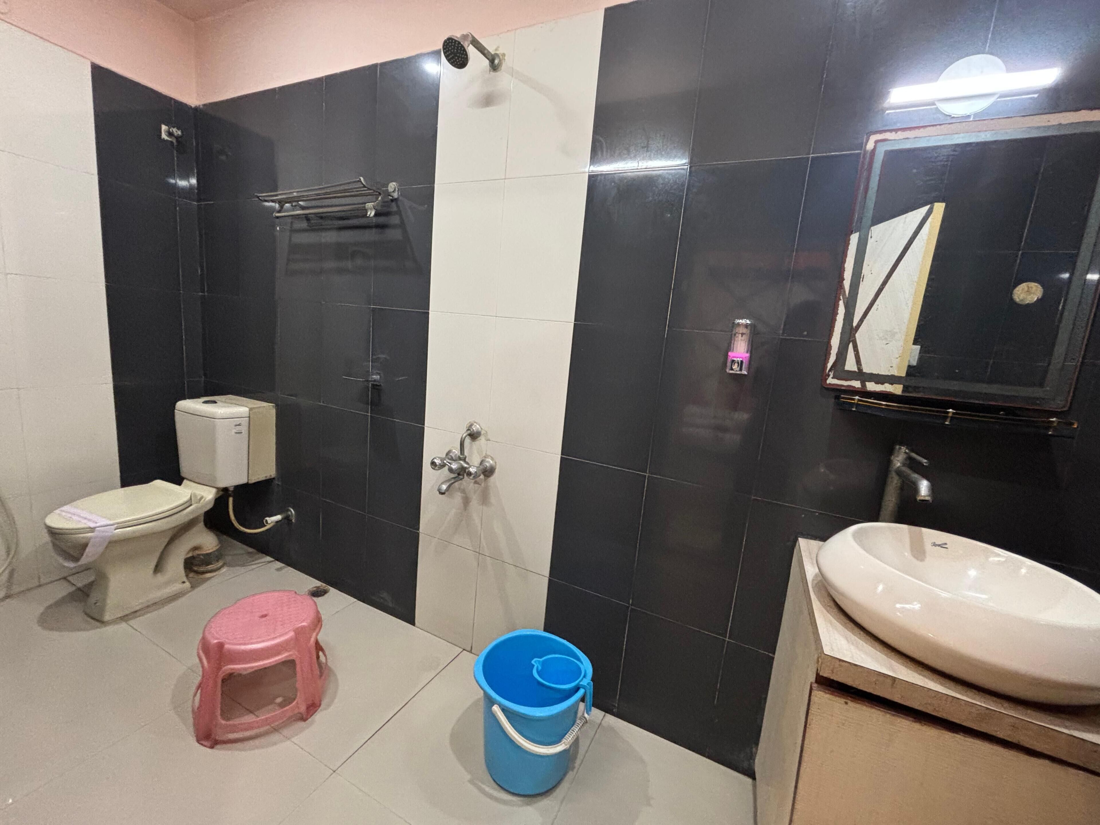 A bathroom with a toilet, sink, mirror, and a shower area.