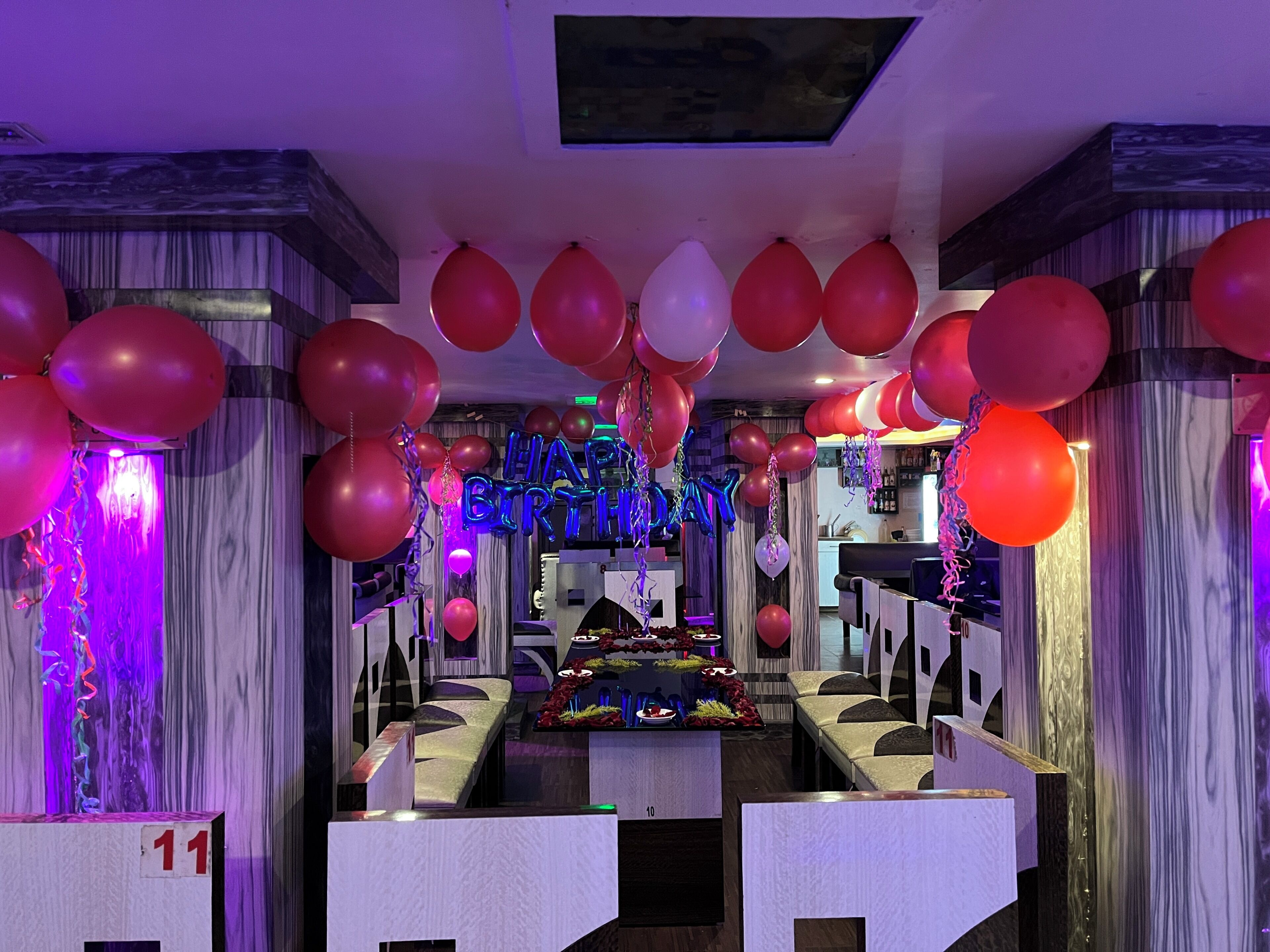 Una habitación con zona de bar, varias opciones de asientos y un escenario para presentaciones.