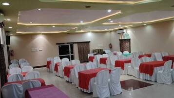 A conference room with rows of tables and chairs, equipped with a projector and a fire extinguisher.
