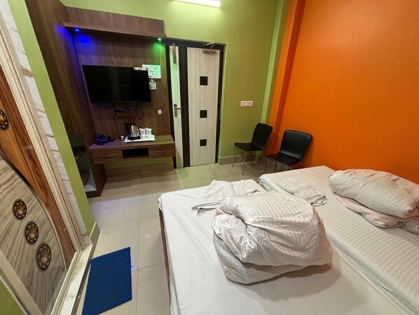 Habitación de hotel con cama, escritorio, televisor de pantalla plana, silla y armario.