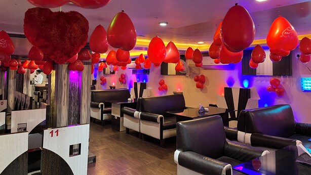 Un hall d’hôtel doté de plusieurs espaces de détente, d’un comptoir d’accueil et d’un grand nombre de ballons rouges.