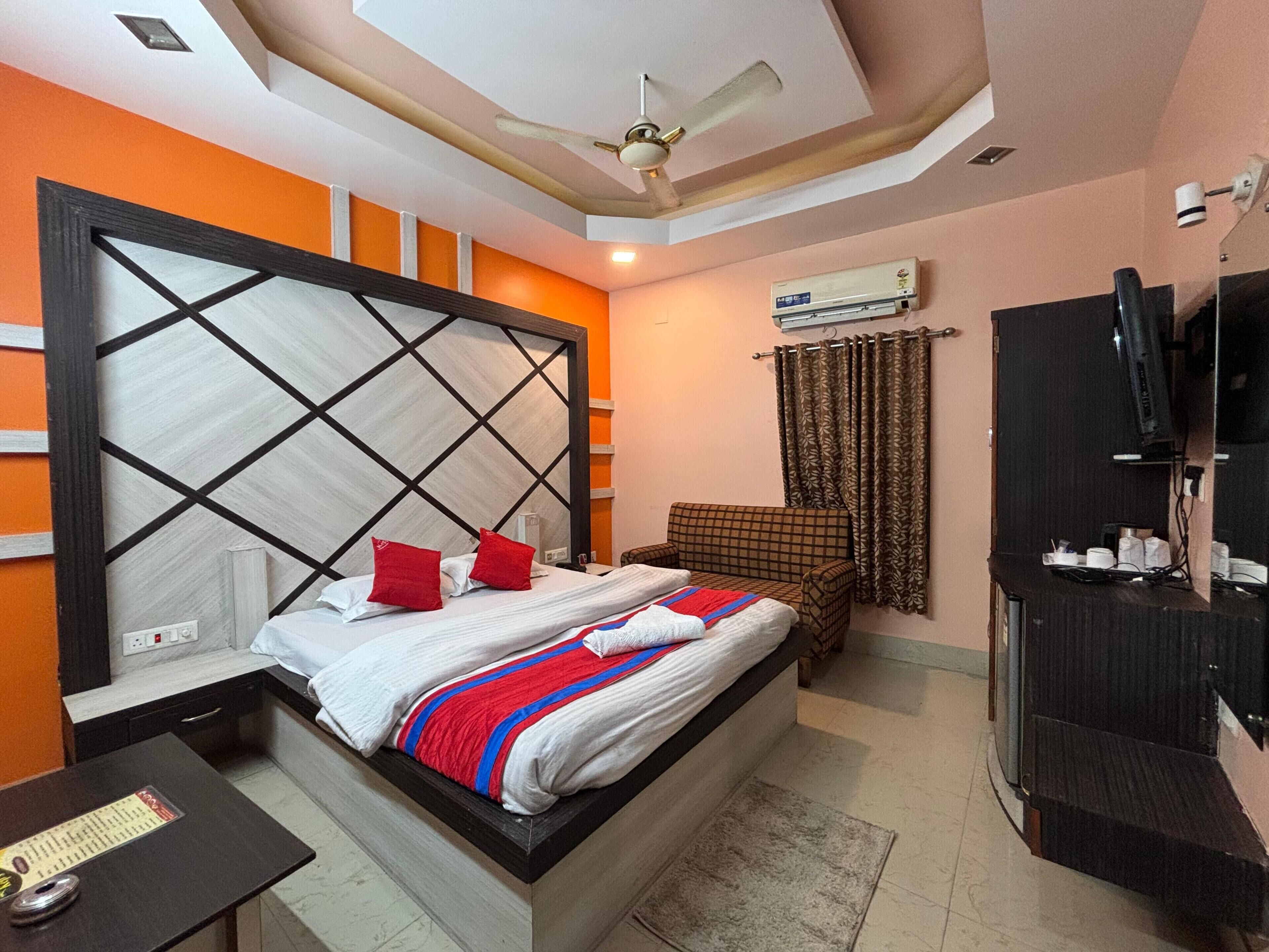 A hotel room with a bed, a TV, a ceiling fan, and an air conditioning unit.