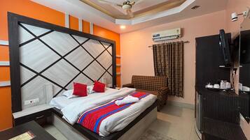 A hotel room with a bed, a TV, a ceiling fan, and an air conditioning unit.