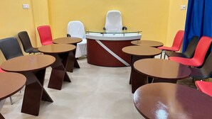 Une salle de conférence dotée d’une table centrale à plateau de verre, entourée de chaises, et d’un mur d’accent de couleur rouge.
