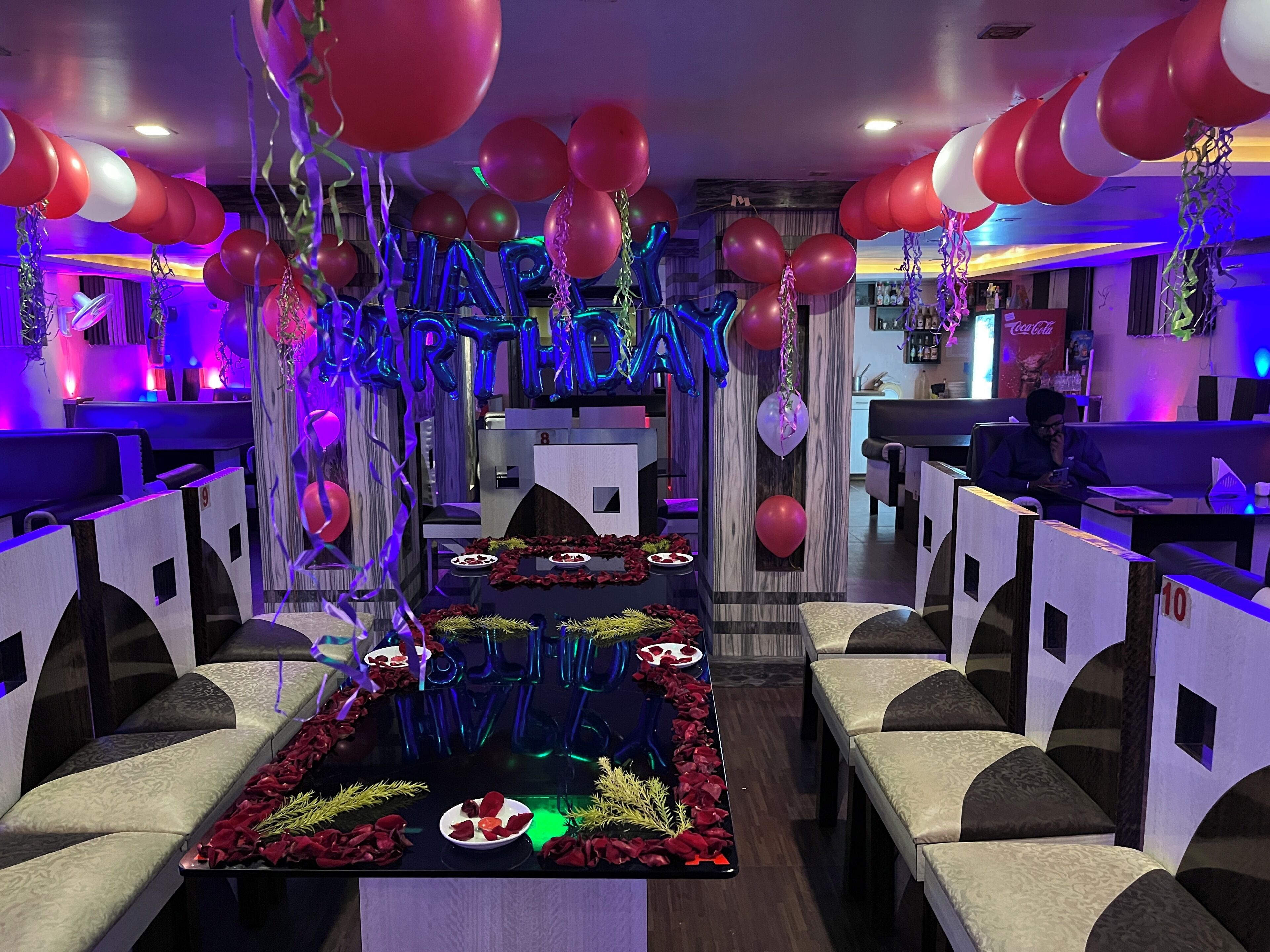 A restaurant with booths, a central table with a floral arrangement, and balloons.