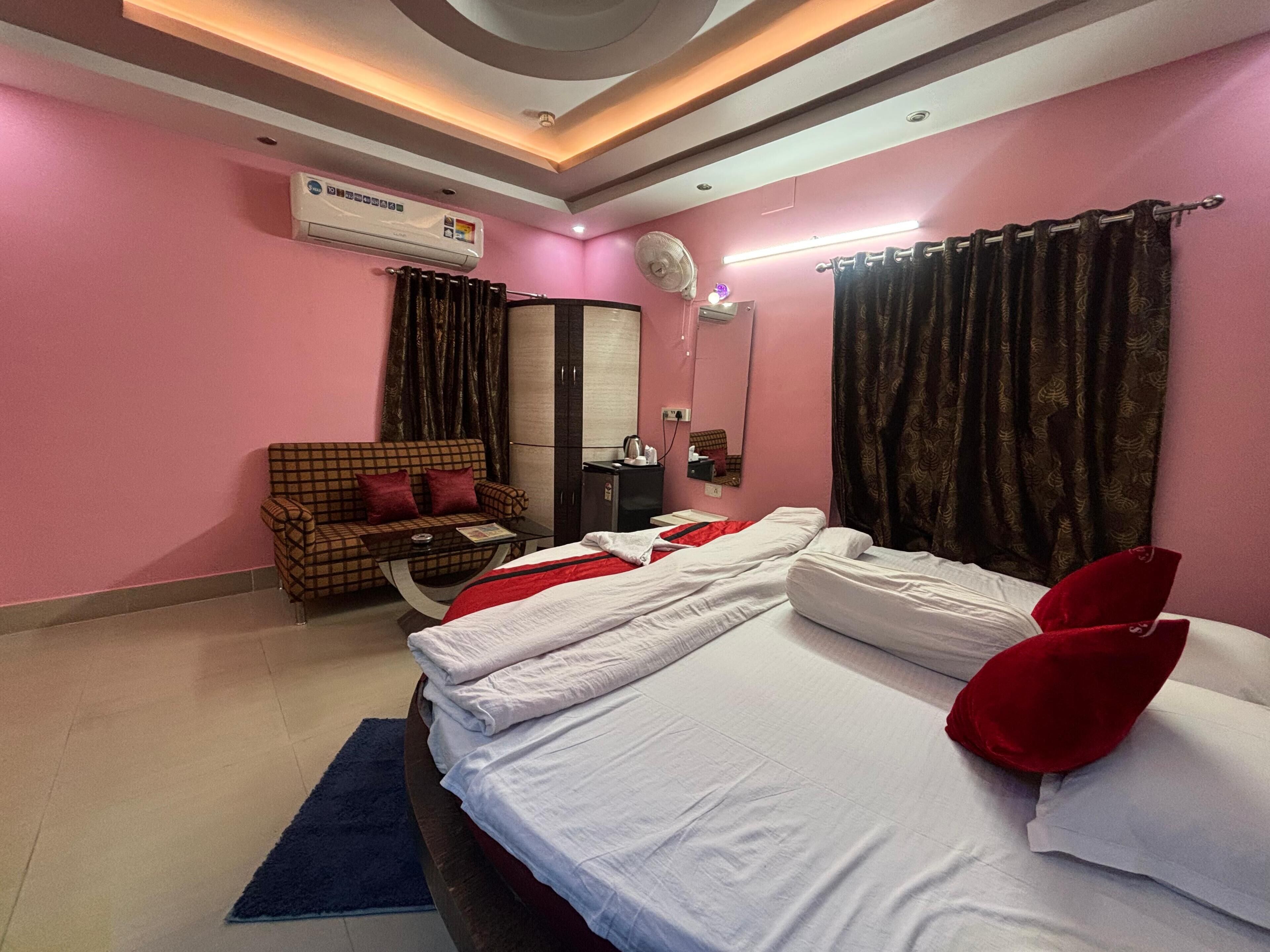 Una habitación de hotel con una cama, un sofá, un espejo y un equipo de aire acondicionado.