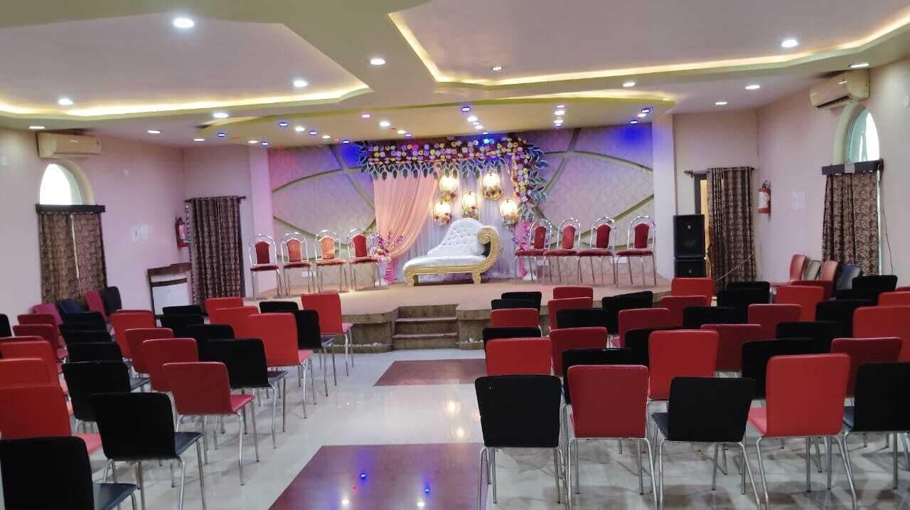 Een vergaderzaal met een podium, rijen stoelen en een decoratieve achtergrond.