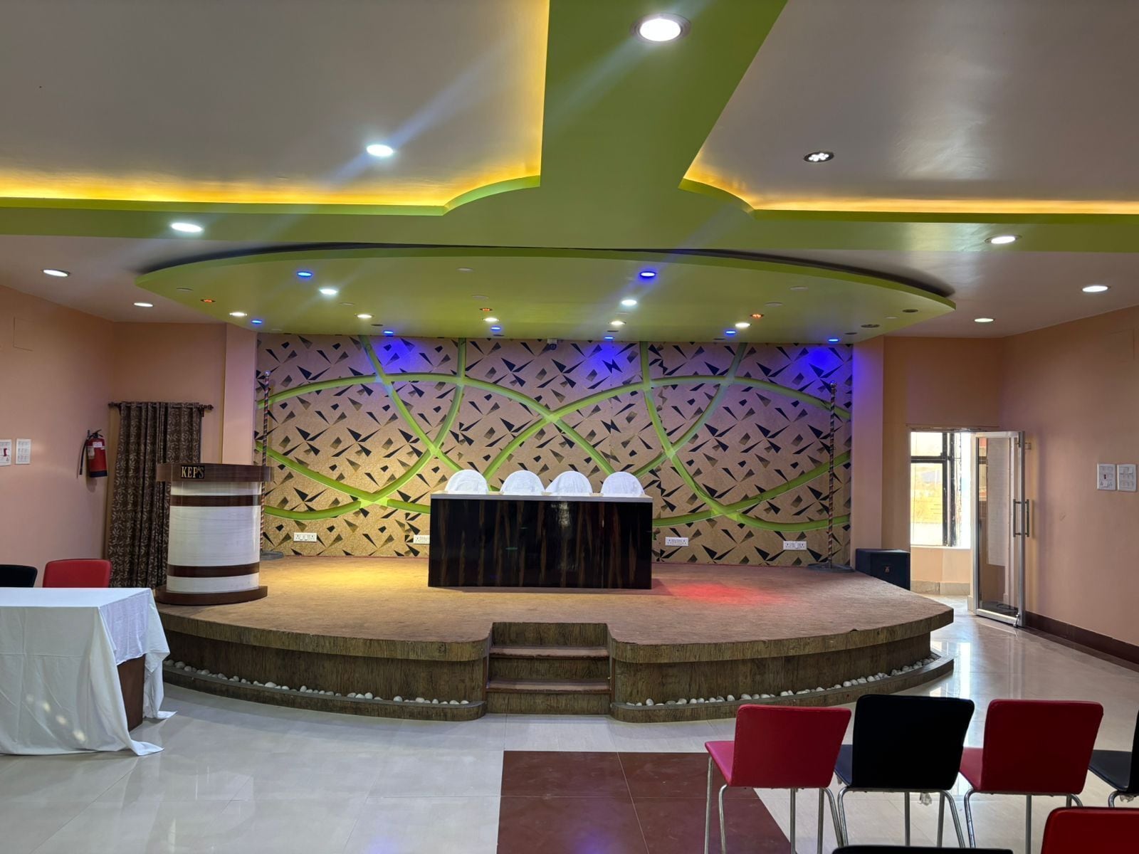 Un salón de conferencias con un escenario, un atril y disposición de asientos.
