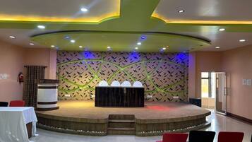Un salón de conferencias con un escenario, un atril y disposición de asientos.