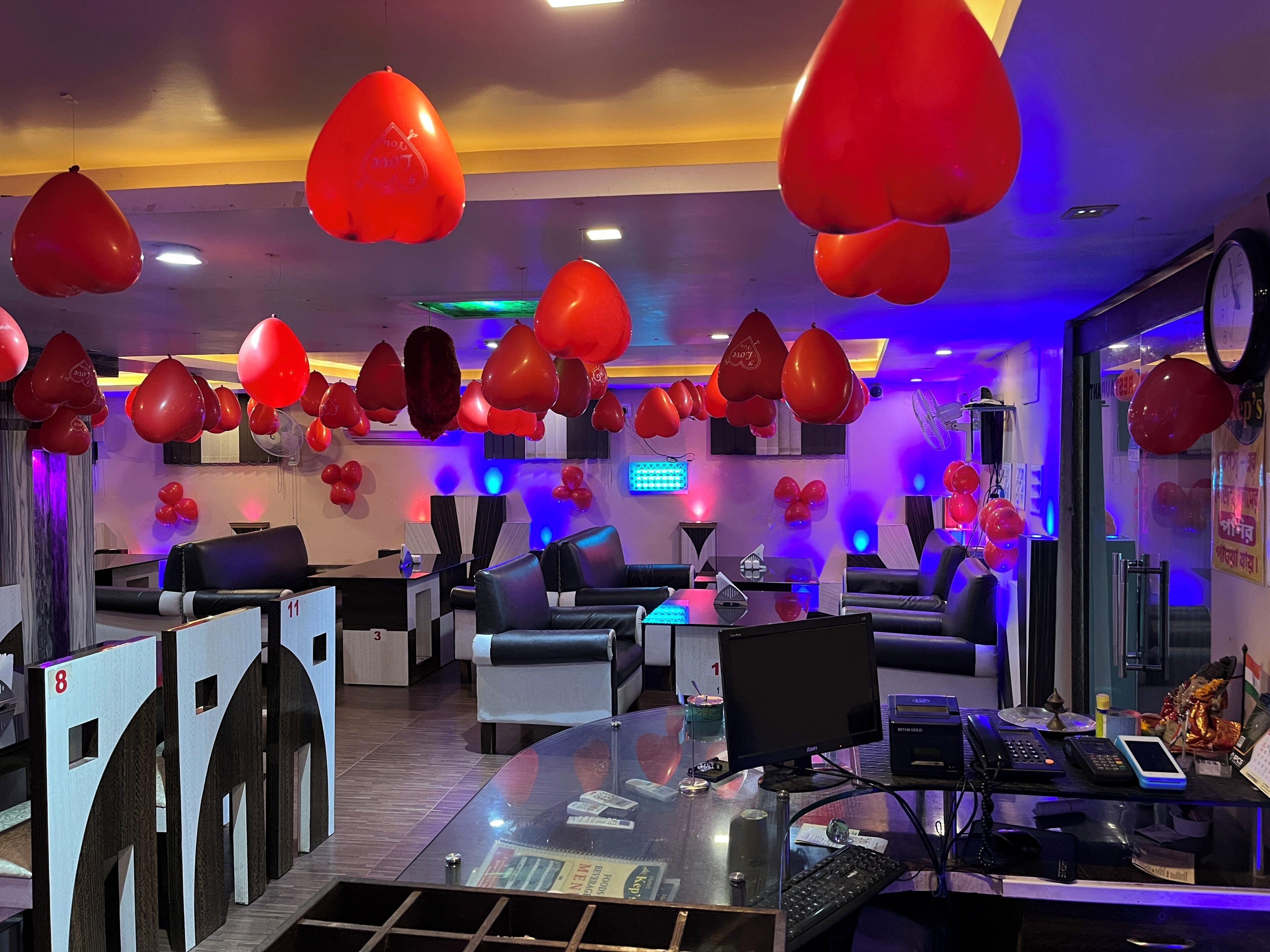 A hotel lobby with red balloons, a reception desk, seating area, and a glass partition.