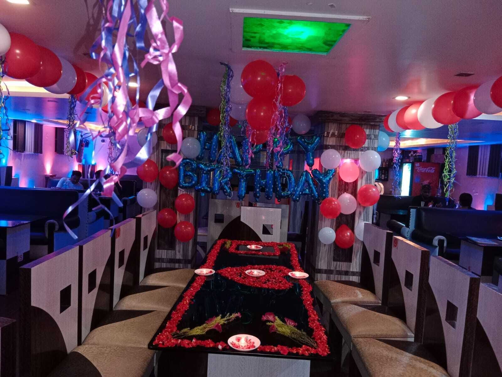 Un restaurante con una mesa larga adornada con flores rojas y velas, rodeado de cabinas.