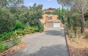 Il s’agit d’une propriété résidentielle dotée d’une allée pavée menant à une maison avec un toit en tuiles et un garage.