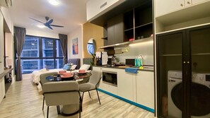Une chambre d’hôtel moderne dotée d’un coin repas, d’une kitchenette et d’une grande fenêtre.
