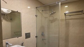 A bathroom with a glass-enclosed shower, a sink, and a mirror. - Super Deluxe Room Mauji's (Prayagraj)