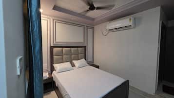A bedroom with a bed, a ceiling fan, an air conditioning unit, and a nightstand.