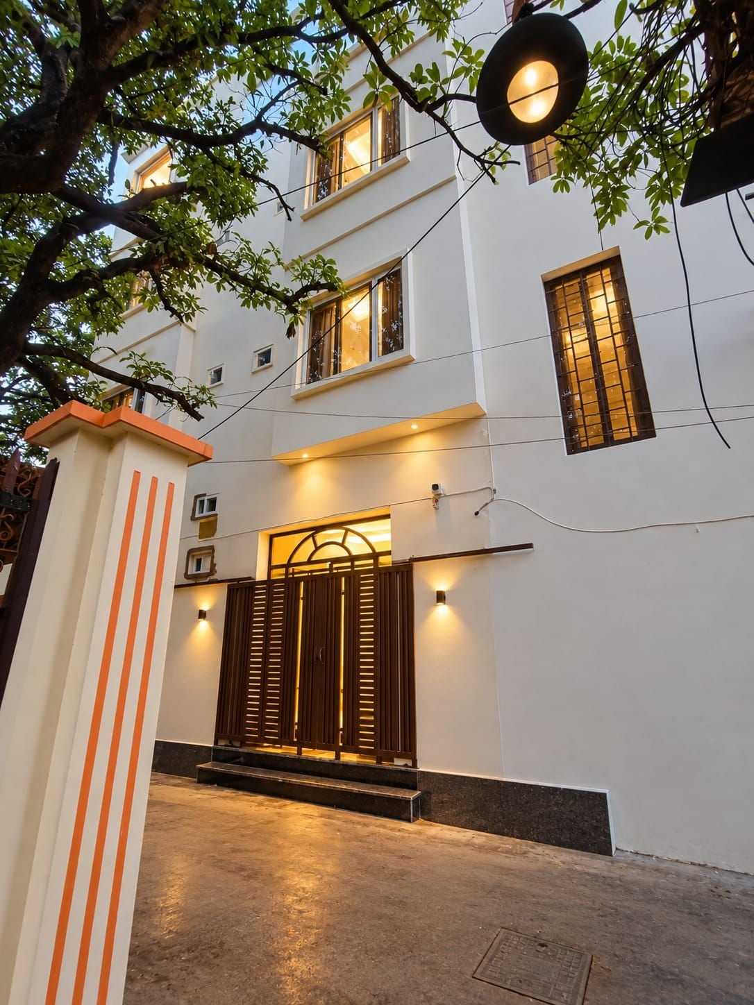 Un edificio con fachada blanca, varias ventanas y una entrada porticada con escalones.