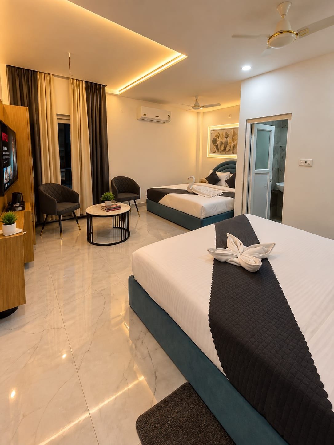 Una habitación de hotel moderna con una cama grande, un escritorio con silla, una mesita y un televisor.