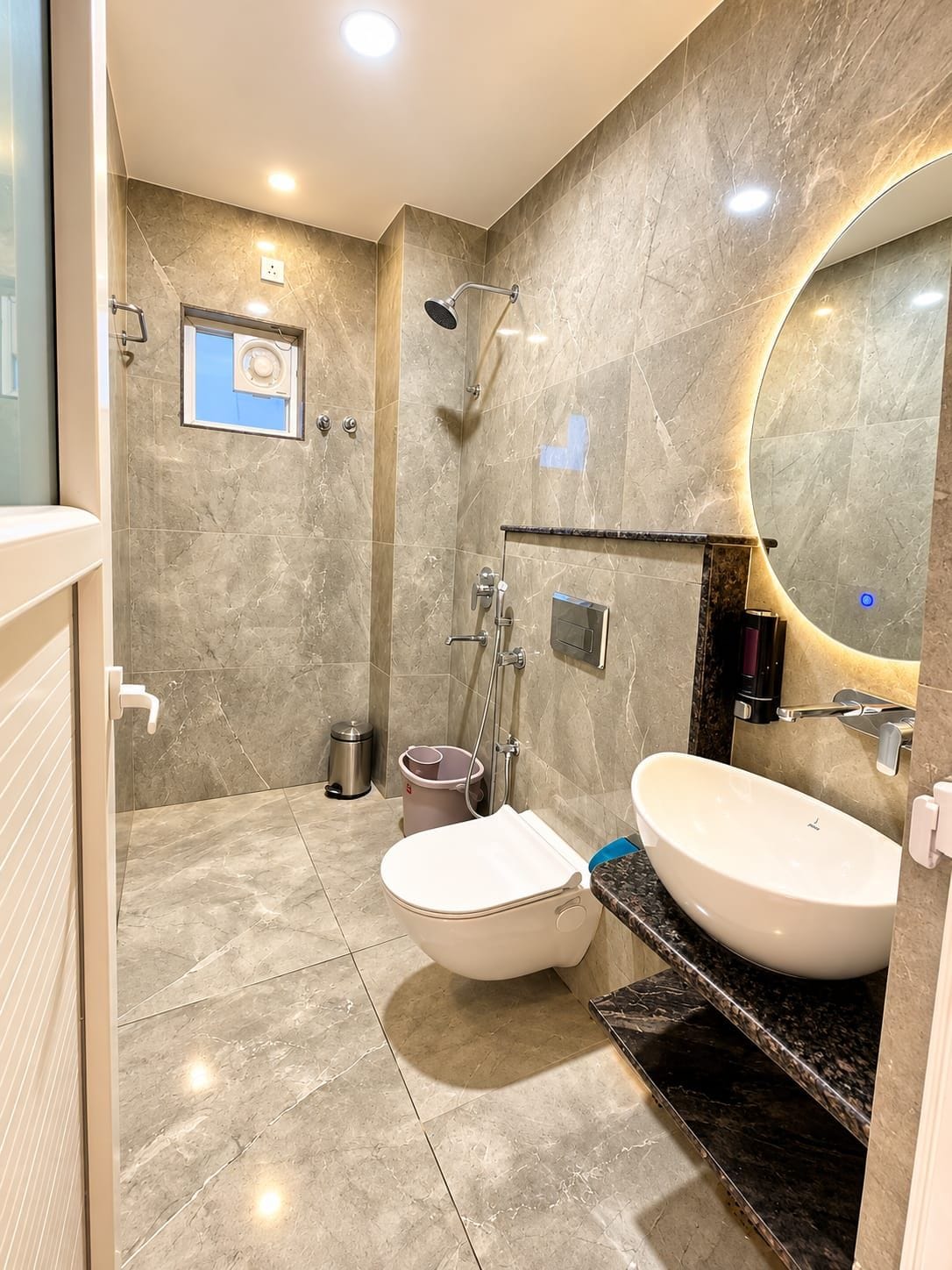 A modern bathroom with a large mirror, a toilet, and a sink.