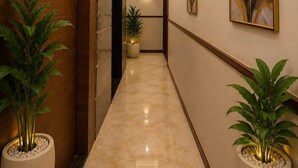 A hallway with a marble floor, wooden doors, and potted plants. - Hotel Rajyashree Retreat (Varanasi)