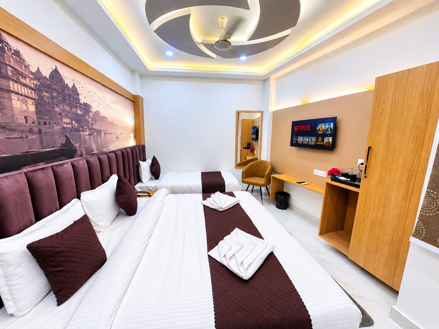 A hotel room with a large bed, a desk, a chair, a television, and a wall-mounted artwork.