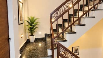 A modern staircase with a wooden railing and a potted plant on the landing.