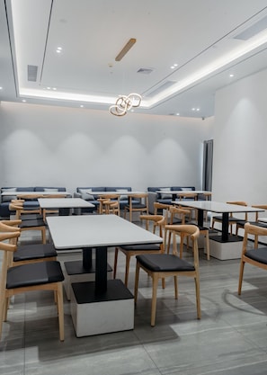 A modern dining area with multiple tables and chairs, a ceiling light fixture, and a vent on the wall. - Paco Hotel Taojin Metro Guangzhou (Guangzhou)