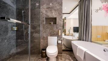 Un baño moderno con ducha envuelta en vidrio, un inodoro, una bañera y un lavamanos con espejo.