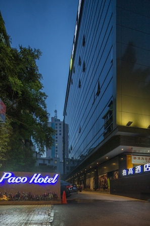 A hotel entrance with a neon sign, a wet pavement, and a building with reflective windows. - Paco Hotel Taojin Metro Guangzhou (Guangzhou)