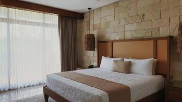 Un dormitorio amplio con una cama grande, ventilador de techo, pared de piedra y vistas al exterior.