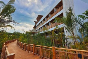 A resort with a wooden boardwalk leading to a multi-story building with balconies. - Hotel Mundo Maya Nuevo Uxmal (Ciudad del Carmen)