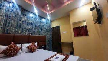 A hotel room with a bed, a ceiling fan, a wall with a patterned design, and a window with curtains.