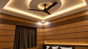 Habitación de hotel con ventilador de techo, luces empotradas y paneles de madera.