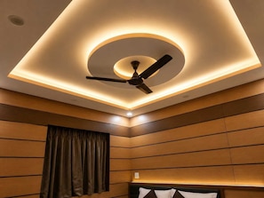 Habitación de hotel con ventilador de techo, luces empotradas y paneles de madera.