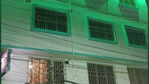 Un edificio de varios pisos con ventanas con barrotes e iluminación verde en el exterior.