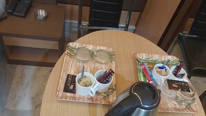 Una mesa de comedor redonda con una cafetera, dos tazas y condimentos sobre individuales.