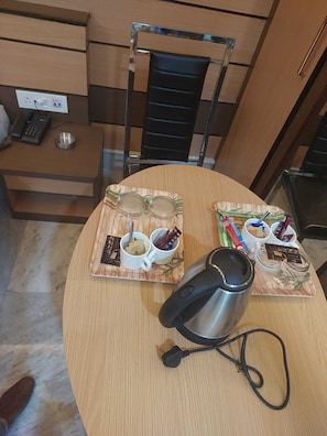 Una mesa de comedor redonda con una cafetera, dos tazas y condimentos sobre individuales.