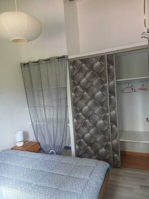 Ein Schlafzimmer mit einem Bett, einem Schrank mit Diamantmuster, einer Pendelleuchte und einem Nachttisch mit Lampe.