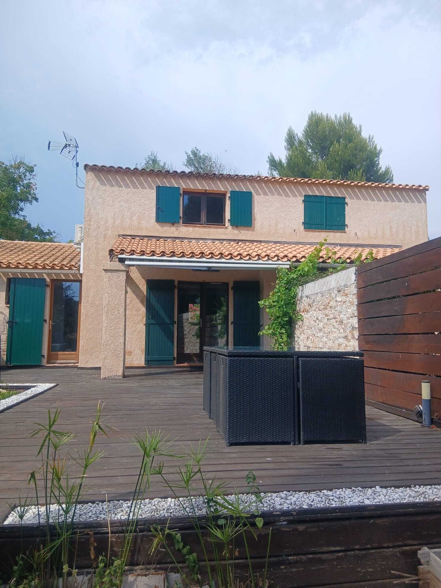 A two-story house with a tiled roof, a covered patio area, and a wooden deck.
