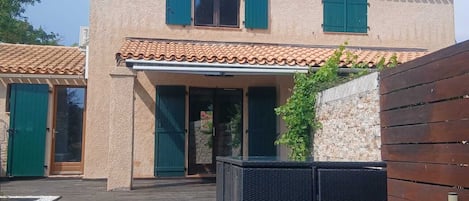 A two-story house with a tiled roof, a covered patio area, and a wooden deck.