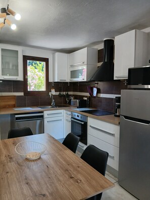 A modern kitchen with white cabinets, a stainless steel dishwasher, a built-in oven, and a black range hood. - A quiet villa overlooking the Gulf of Terre Blanche in the town of Tourrettes. (Tourrettes)