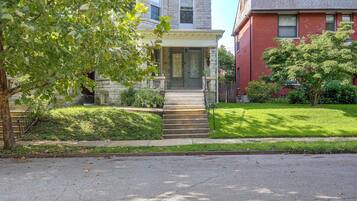 A two-story house with a stone facade, a front porch, and a well-maintained lawn.
