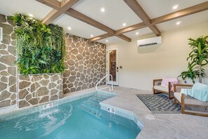 Une piscine intérieure avec un mur en pierre et un plafond en bois.
