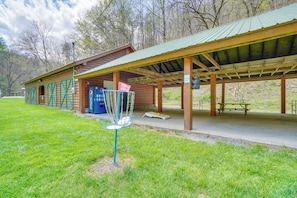 Ein rustikales Pavillon mit überdachter Sitzgruppe, einem Picknicktisch und einem Basketballkorb.