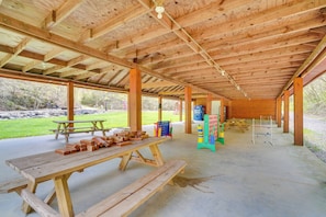Ein offenes Holzpavillon mit Picknicktischen und einer Kletterwand.